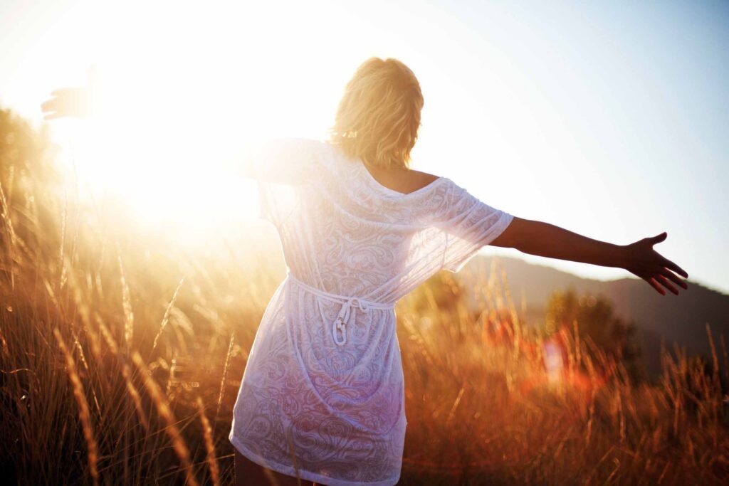 photo d'une femme de dos avec une robe blanche en face du soleil